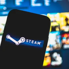 Smartfon z logo Steam na tle ekranu z grami.