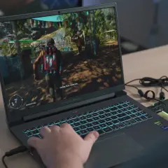 Gracz gra w grę na laptopie z podświetlaną klawiaturą.
