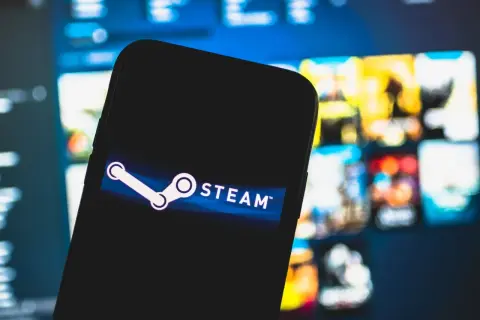 Smartfon z logo Steam na tle ekranu z grami.