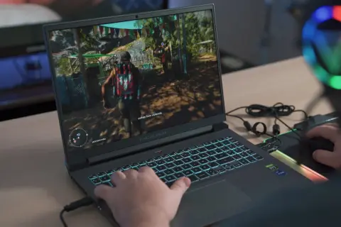 Gracz gra w grę na laptopie z podświetlaną klawiaturą.