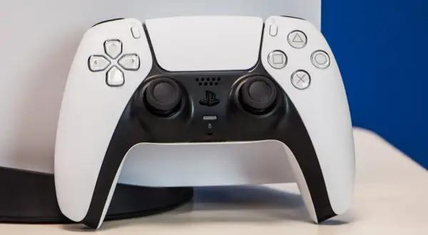 Biały kontroler DualSense od PS5 na jasnym tle.