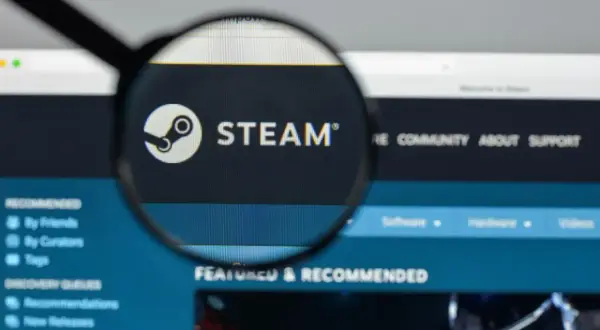 Lupa powiększa logo Steam na ekranie komputera.