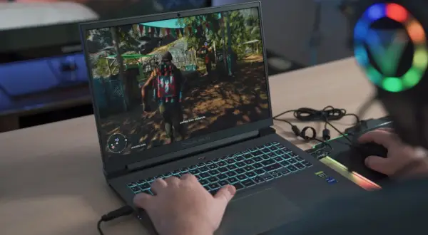 Gracz gra w grę na laptopie z podświetlaną klawiaturą.