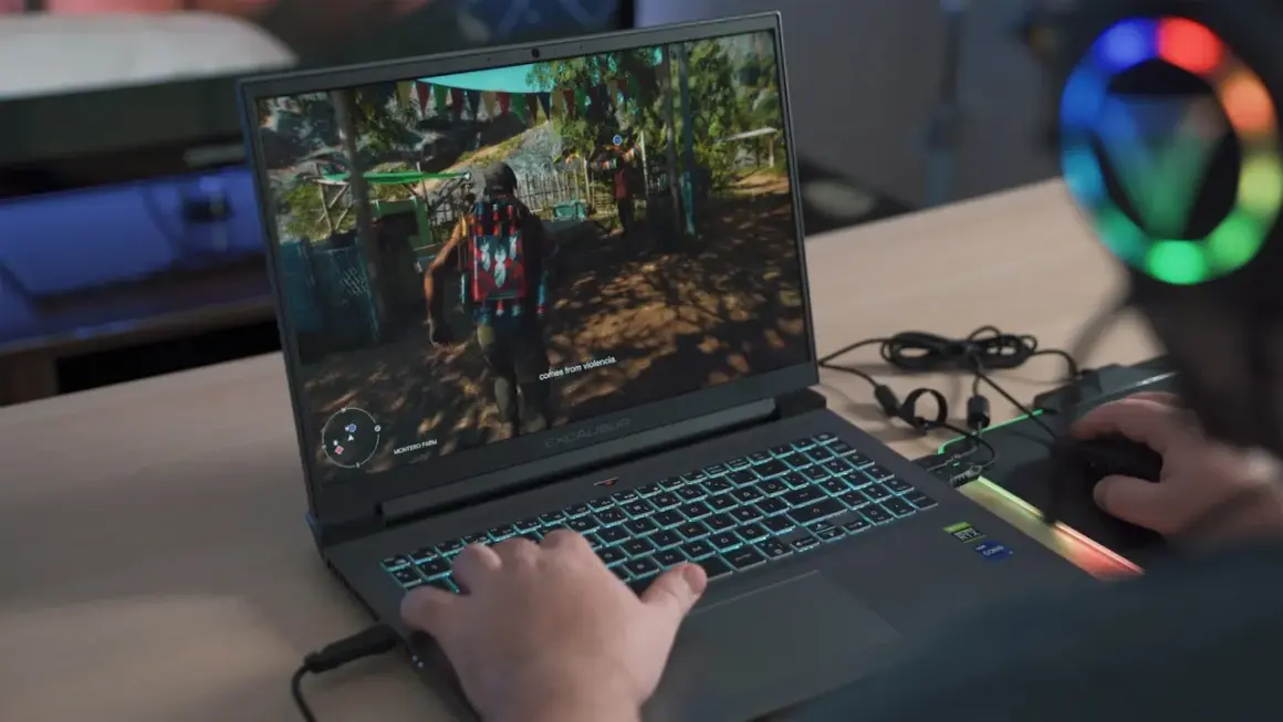 Gracz gra w grę na laptopie z podświetlaną klawiaturą.